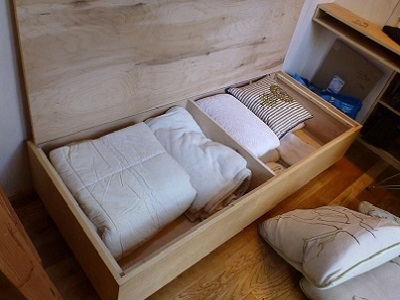 This sofa bench functions for day and night-time use. It's ready for overnight guests, including storage filled with all bedding. Specific storage is essential in a tiny house. (Sol Haus)